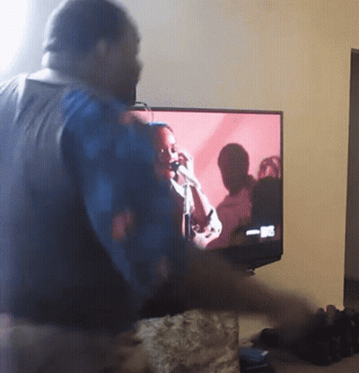 A Man Stands In Front Of A Tv Screen That Says ' Nbc ' On It GIF