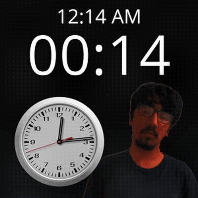 A Man Stands In Front Of A Wall Clock That Says 12:14 Am GIF