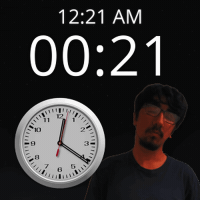 A Man Stands In Front Of A Wall Clock That Says 12:21 Am GIF