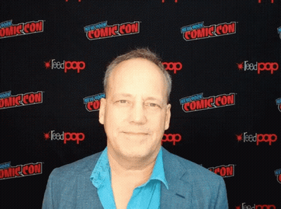 A Man Stands In Front Of A Wall That Says Comic Con On It GIF