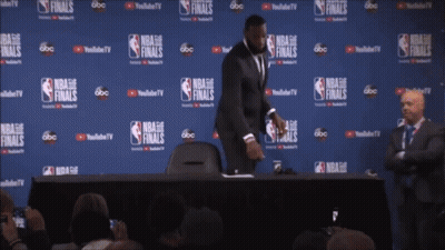 A Man Stands In Front Of A Wall That Says Nba Finals On It GIF