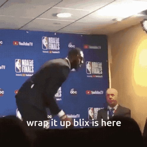 A Man Stands In Front Of A Wall That Says Nba Finals On It GIF