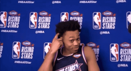 A Man Stands In Front Of A Wall With Logos For Rising Stars GIF