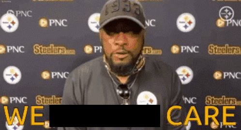 A Man Stands In Front Of A Wall With Steelers Logos On It GIF