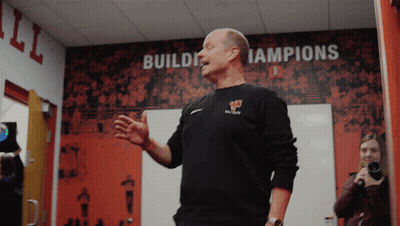 A Man Stands In Front Of A Wall With The Words Build Champions On It GIF
