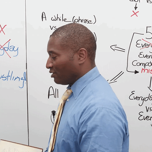 A Man Stands In Front Of A White Board That Says A While ( Phrase ) On It GIF
