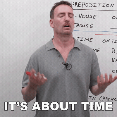 A Man Stands In Front Of A White Board With The Words " It 'S About Time " Written On It GIF