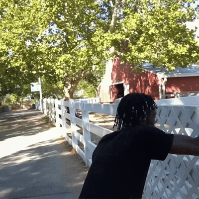 A Man Stands In Front Of A White Picket Fence GIF