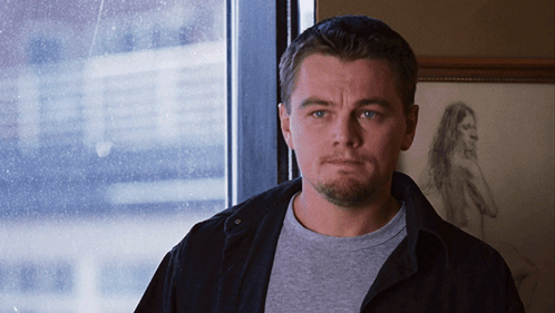 A Man Stands In Front Of A Window With A Drawing Of A Woman Behind Him GIF