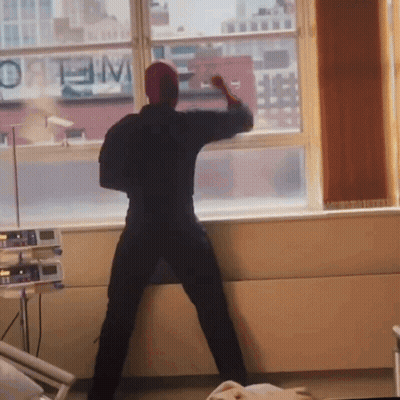 A Man Stands In Front Of A Window With A Sign That Says Optimum GIF