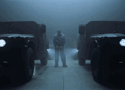 A Man Stands In Front Of Two Military Vehicles GIF