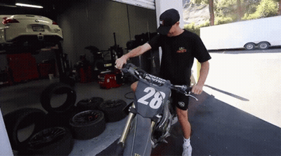 A Man Stands Next To A Motorcycle With The Number 28 On The Front GIF