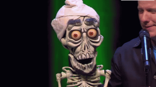A Man Stands Next To A Skeleton Wearing A Turban GIF