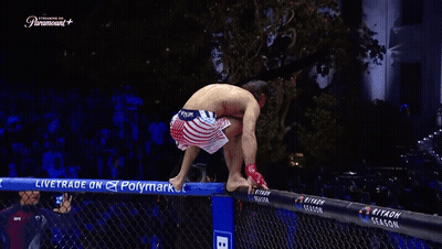 A Man Stands On A Fence With His Arms Outstretched In Front Of A Paramount Sign GIF