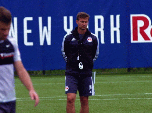 A Man Stands On A Field In Front Of A New York Sign GIF