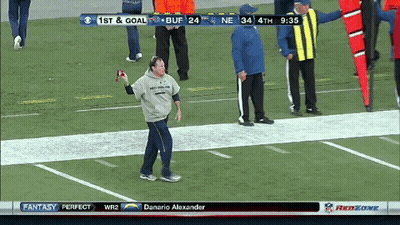 A Man Stands On A Football Field Holding A Ball In Front Of A Scoreboard That Says 1St And Goal GIF