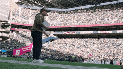 A Man Stands On A Football Field In Front Of A Sign That Says T Mobile GIF