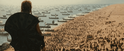 A Man Stands On A Hill Overlooking A Large Body Of Water With Many Boats In It GIF
