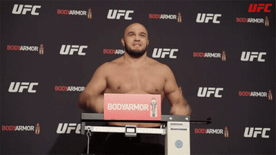 A Man Stands On A Scale In Front Of A Wall That Says Ufc GIF