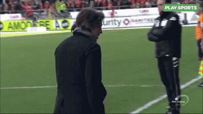 A Man Stands On A Soccer Field With A Play Sports Sign Above Him GIF