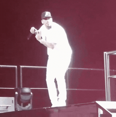 A Man Stands On A Stage Holding A Microphone In His Hand GIF