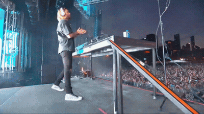 A Man Stands On A Stage In Front Of A Crowd And A Sign That Says ' Chicago Radio ' On It GIF