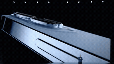 A Man Stands On A Stage In Front Of A Large Phone GIF