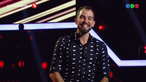 A Man Stands On A Stage In Front Of A Microphone With The Hashtag La Voz Argentina GIF