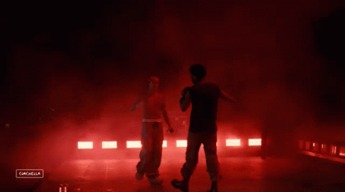 A Man Stands On A Stage With Red Lights Behind Him And The Words Cancella On The Bottom GIF