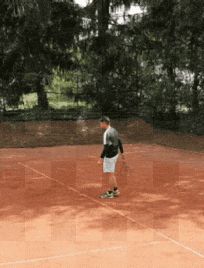 A Man Stands On A Tennis Court Holding A Racket GIF