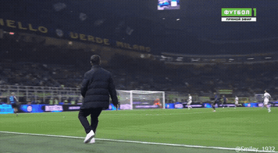 A Man Stands On The Edge Of A Soccer Field In Front Of A Banner That Says Anello Verde Milano GIF