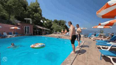 A Man Stands On The Edge Of A Swimming Pool Looking At A Float In The Water GIF