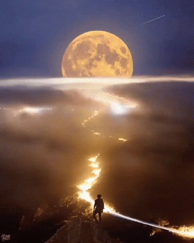 A Man Stands On Top Of A Mountain Looking At The Full Moon GIF