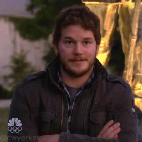 A Man Stands With His Arms Crossed In Front Of A Sign That Says Nbc GIF