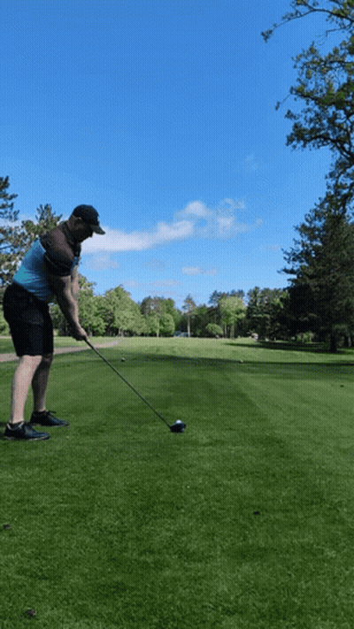 A Man Swings A Golf Club At A Golf Ball GIF