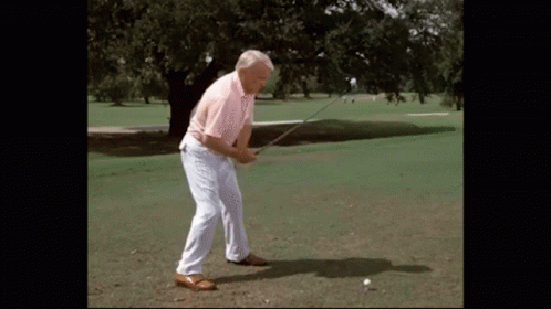 A Man Swings A Golf Club At A Golf Ball GIF