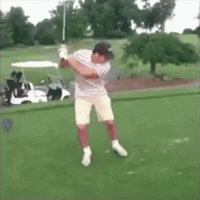 A Man Swings A Golf Club On A Golf Course In Front Of A Golf Cart GIF