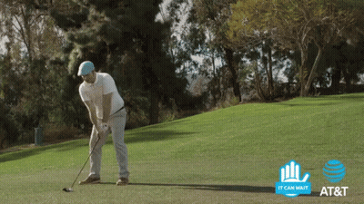 A Man Swings A Golf Club On A Golf Course With An At & T Logo In The Background GIF