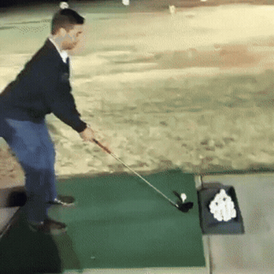 A Man Swings A Golf Club On A Green Mat GIF