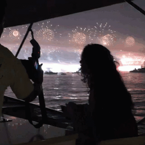 A Man Takes A Picture Of A Woman Watching Fireworks GIF