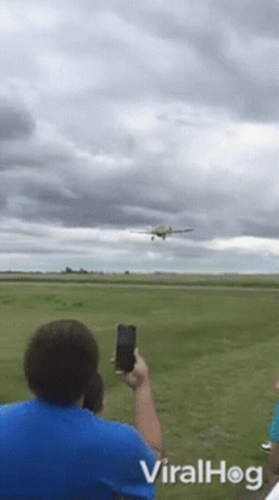 A Man Takes A Picture Of An Airplane Taking Off From A Runway With Viralhog Written On The Bottom GIF