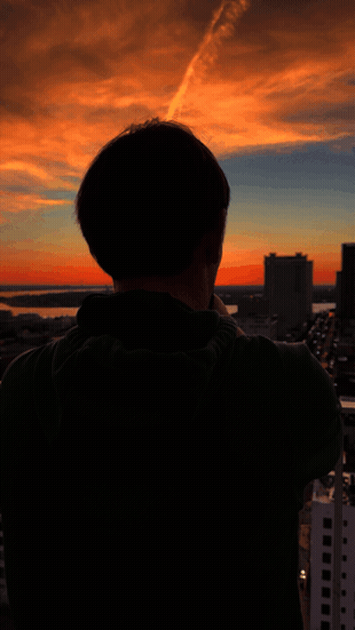 A Man Taking A Picture Of A Sunset With His Cell Phone GIF