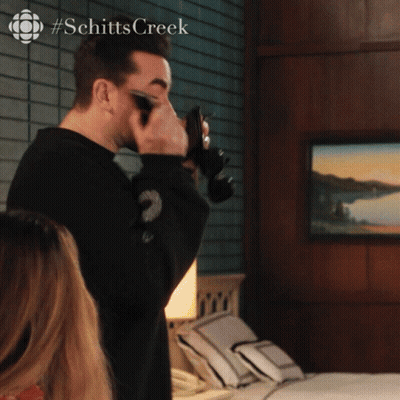 A Man Taking A Picture With A Camera With #Schitts Creek On The Bottom GIF
