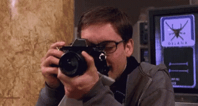 A Man Taking A Picture With A Camera With The Word Oceana On The Screen Behind Him GIF