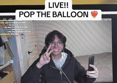 A Man Taking A Selfie In Front Of A Screen That Says " Live Pop The Balloon " GIF