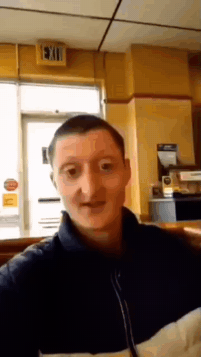 A Man Taking A Selfie In Front Of A Sign That Says Exit GIF