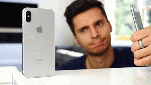A Man Taking A Selfie With An Iphone In The Background GIF