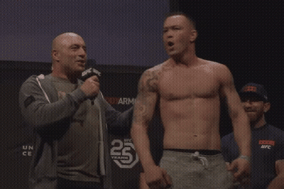 A Man Talking Into A Microphone In Front Of A Sign That Says 25 Years On It GIF