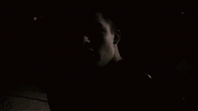 A Man Talking On A Cell Phone In A Dark Room GIF