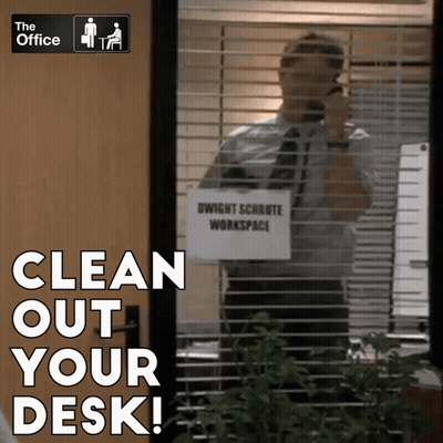 A Man Talking On A Cell Phone In Front Of A Sign That Says " Clean Out Your Desk " GIF